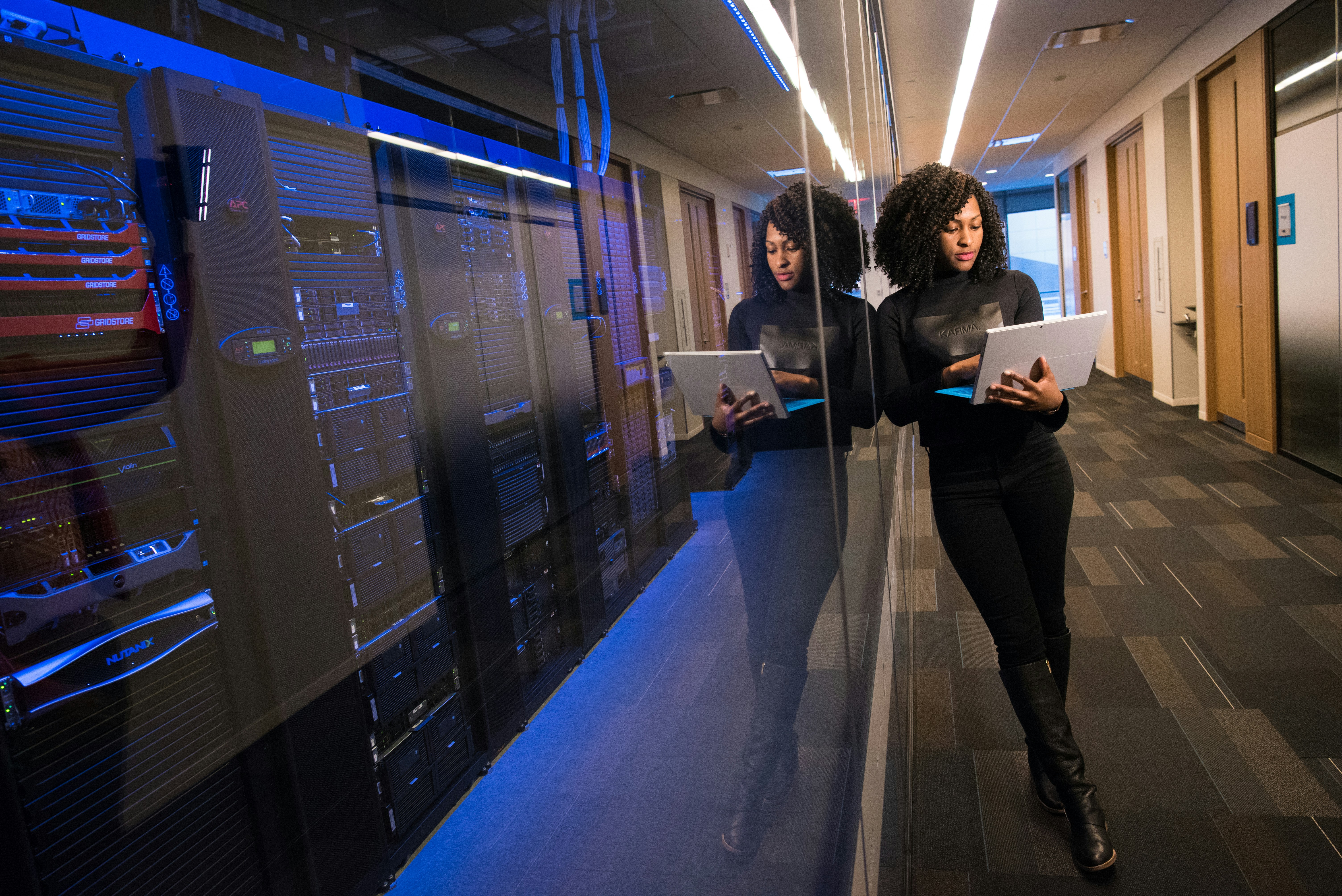 Woman standing up looking at laptop in office corridor