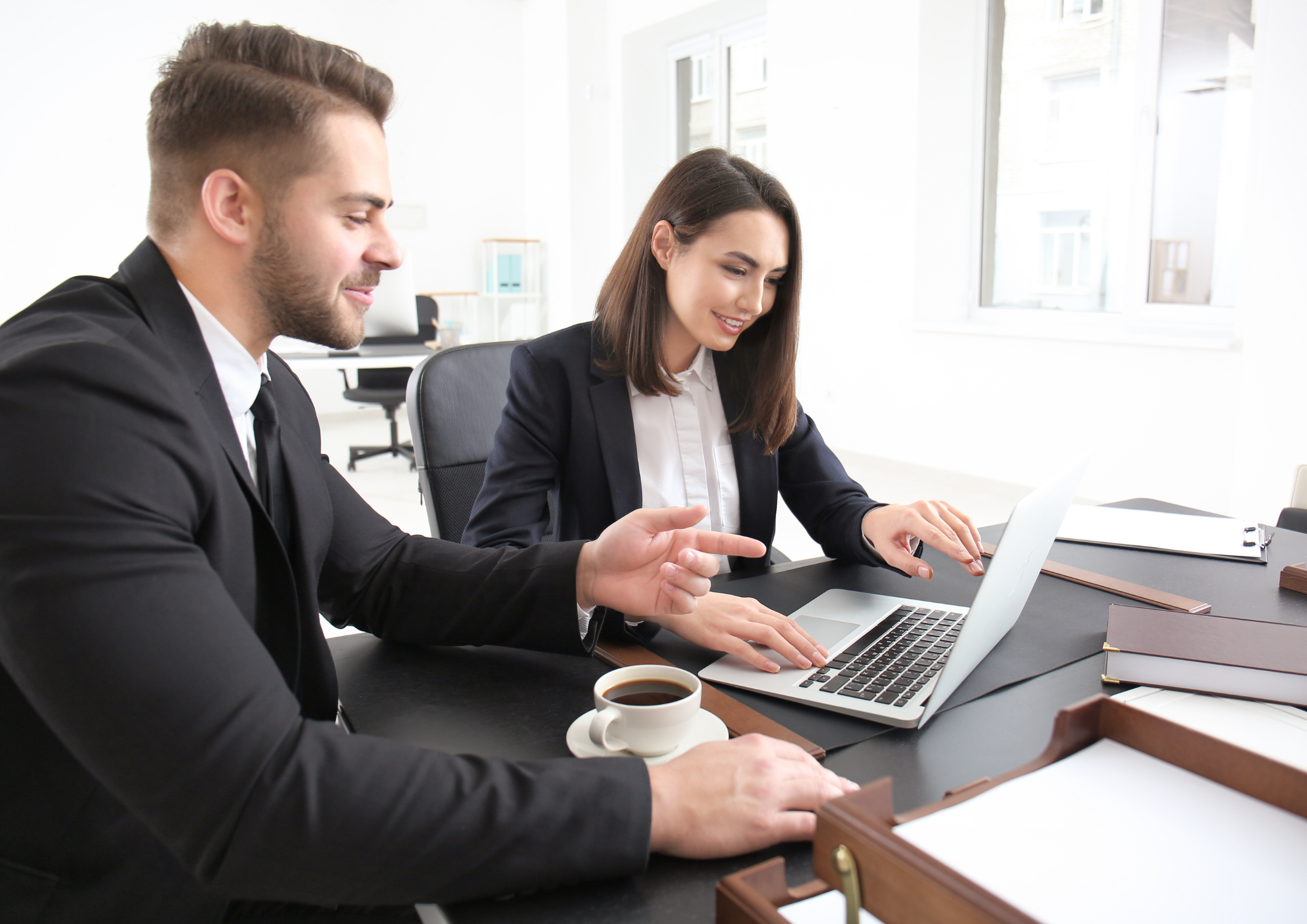 Smartly dressed man and woman in office setting looking at a computer