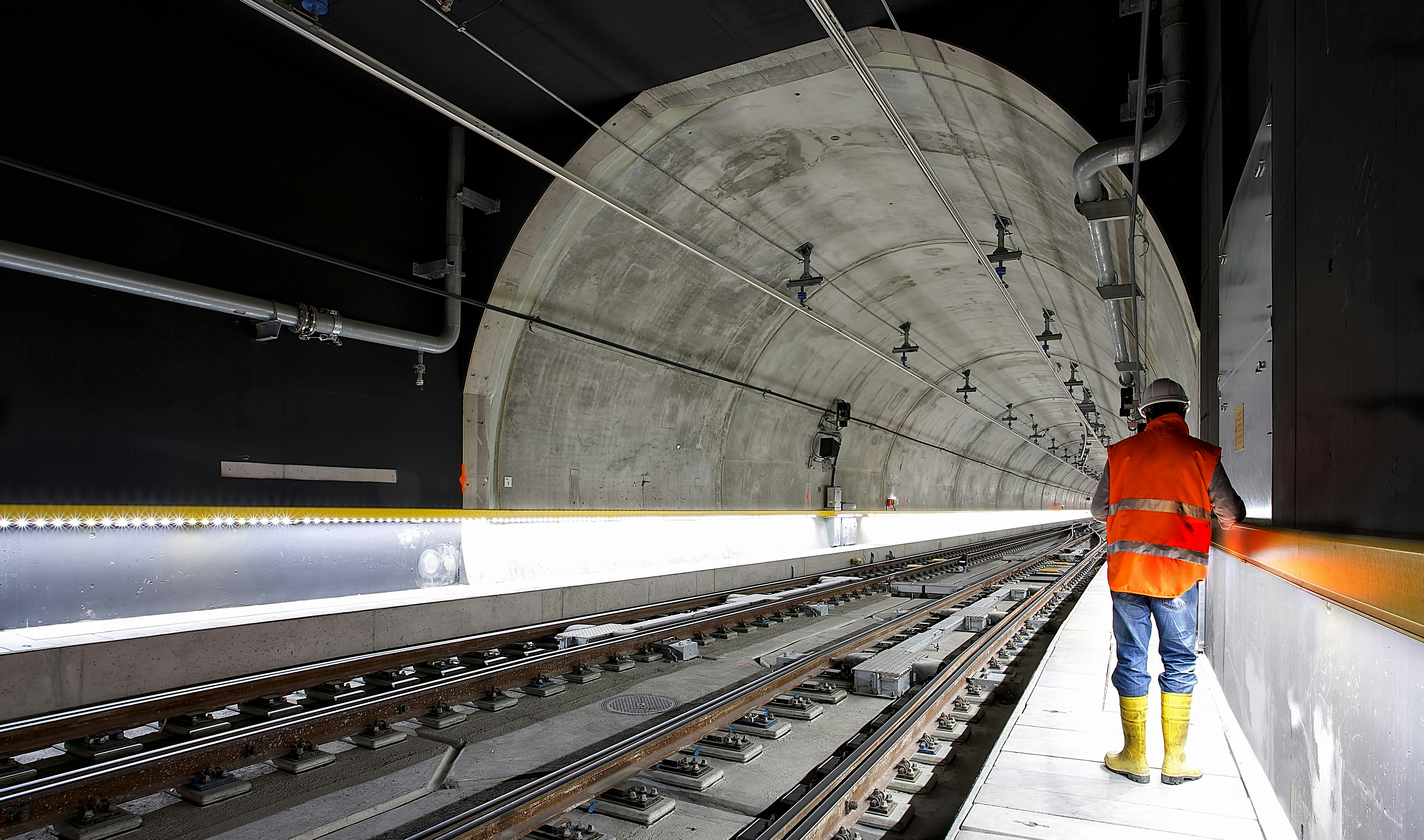 A man in a high vis jacket and hard hat in a rail tunnel