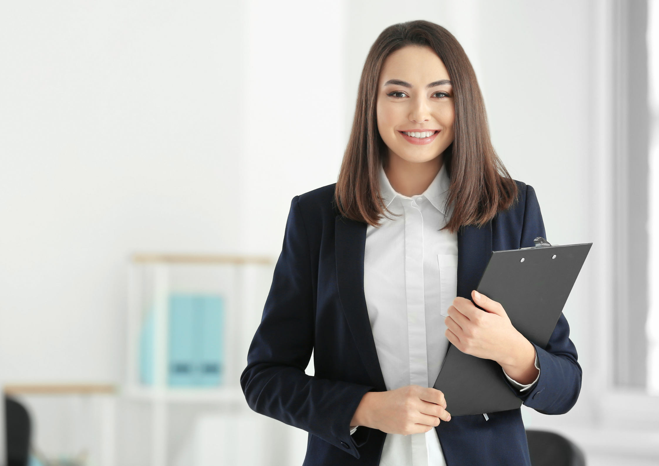 Smartly dressed woman smiling into camera holding clipboard