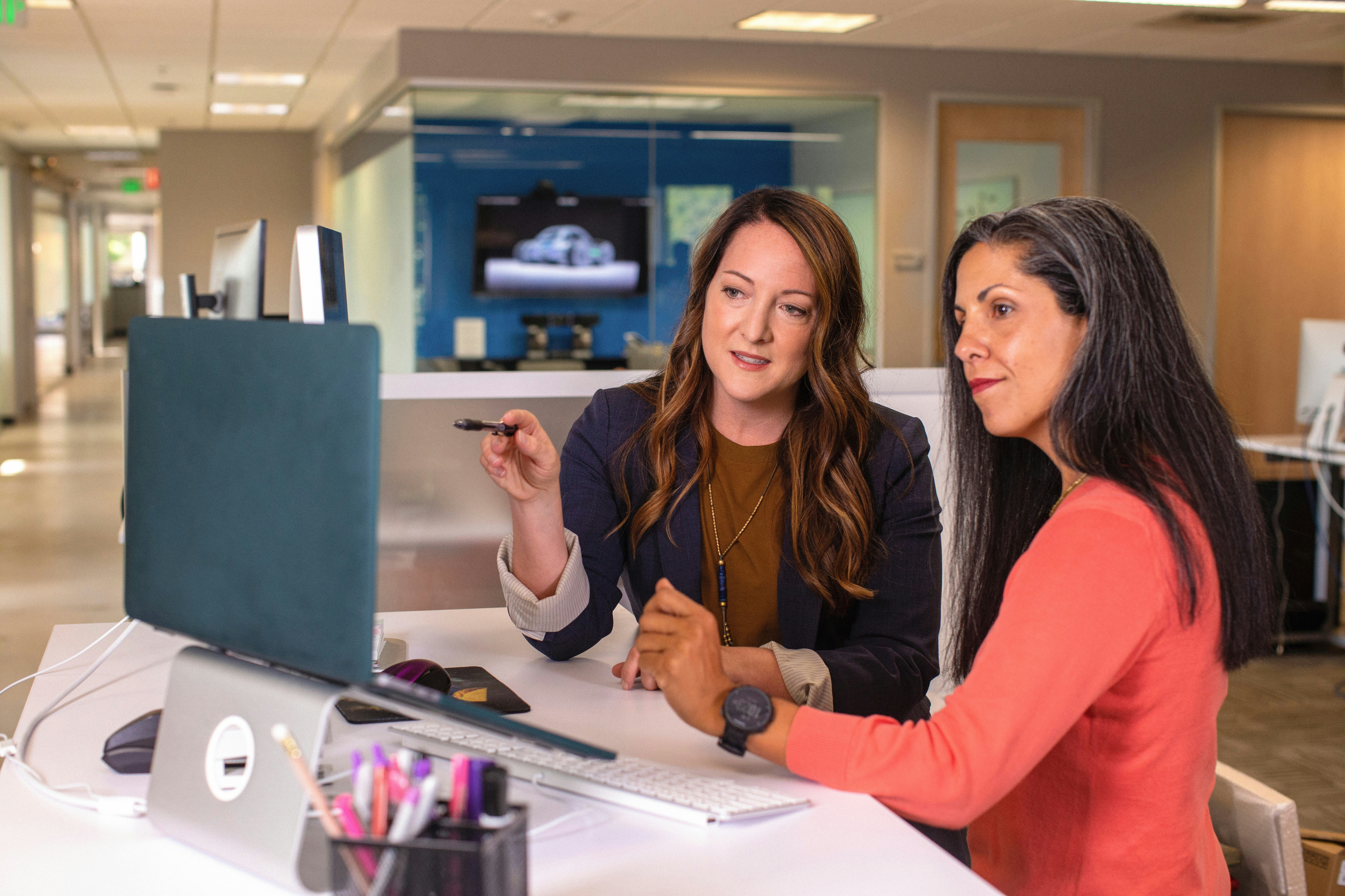 Two women in a office setting both looking at a computer