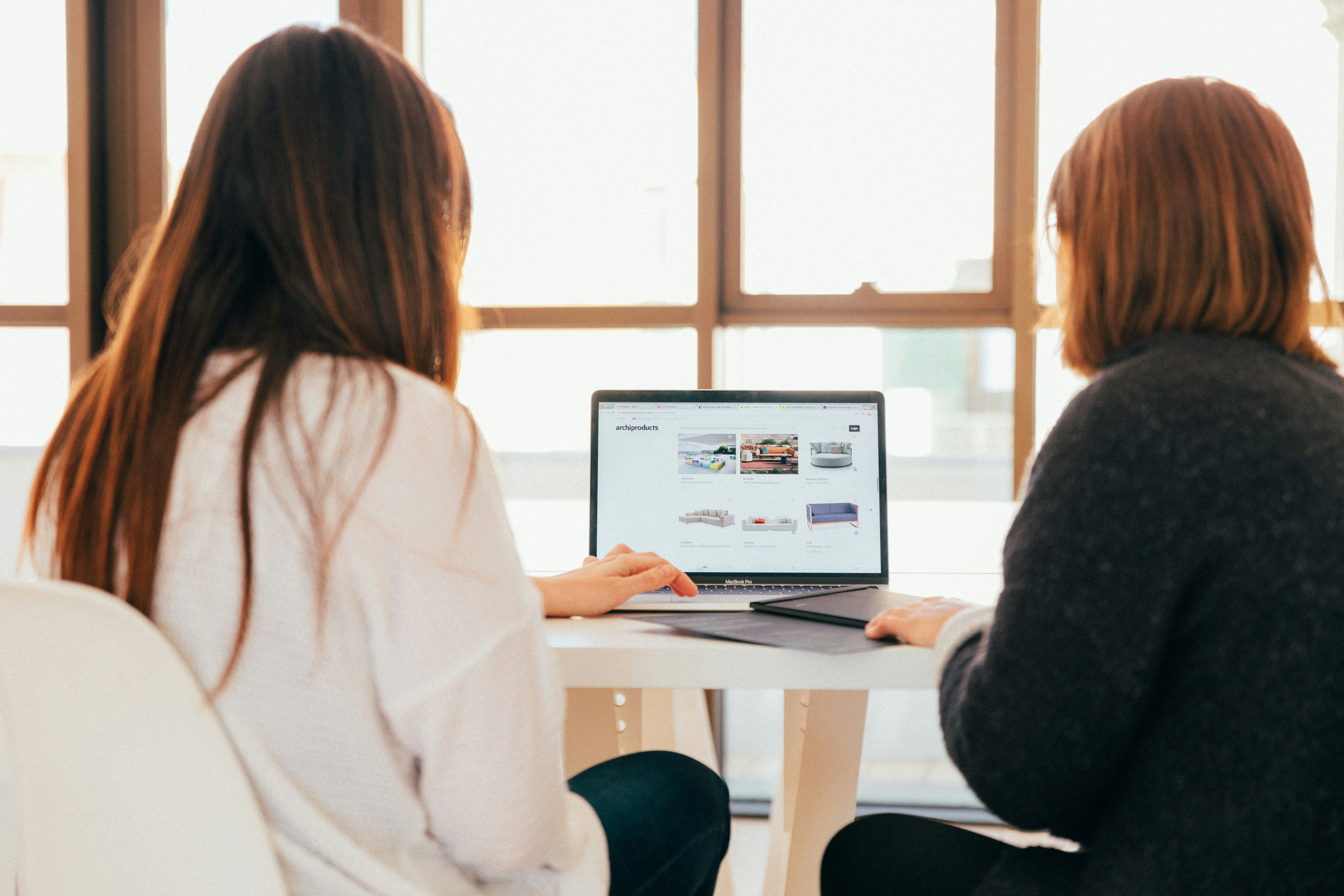 Two women looking at computer with their backs to the camera