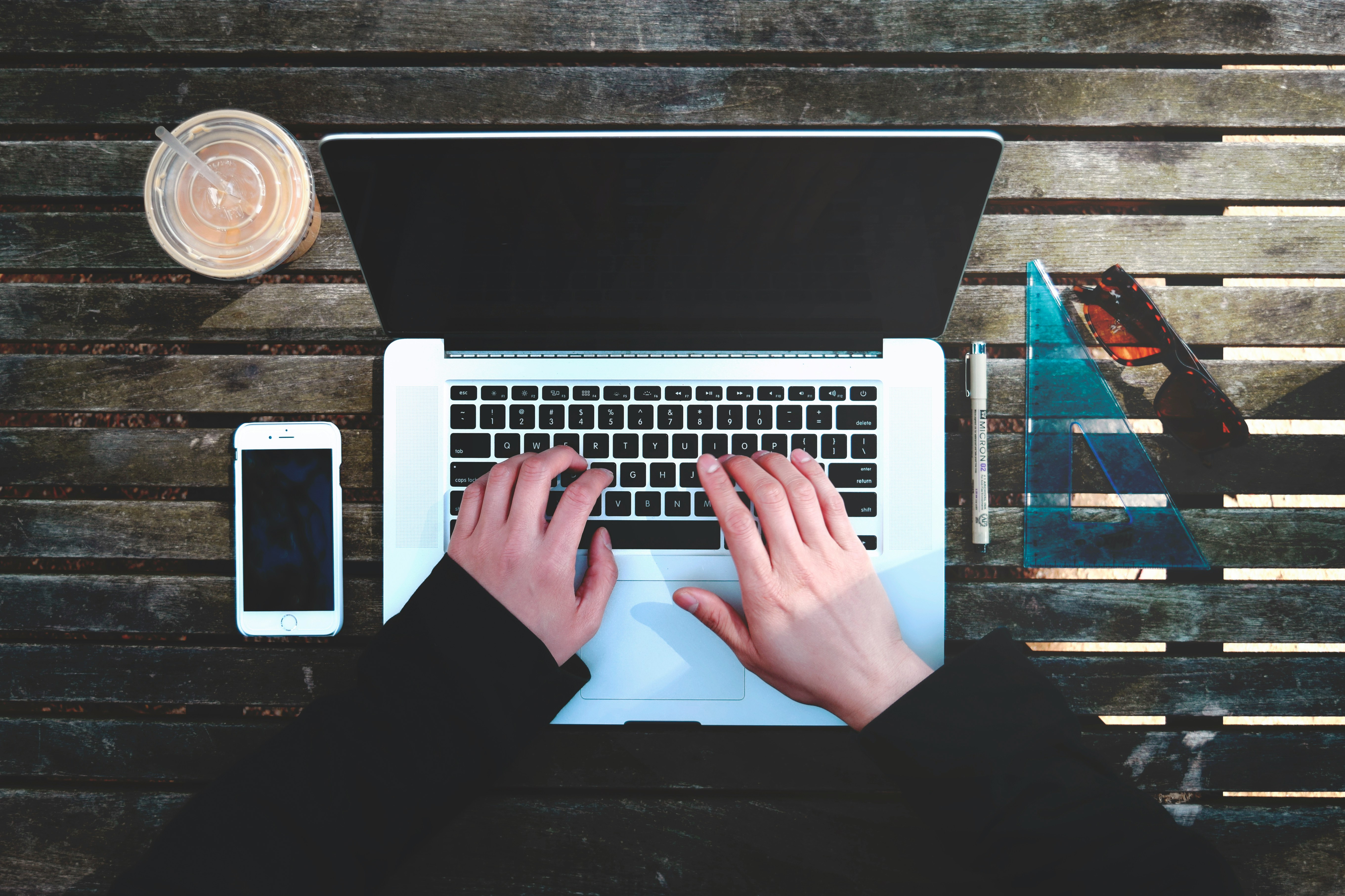 Hands typing on laptop next to a mobile phone